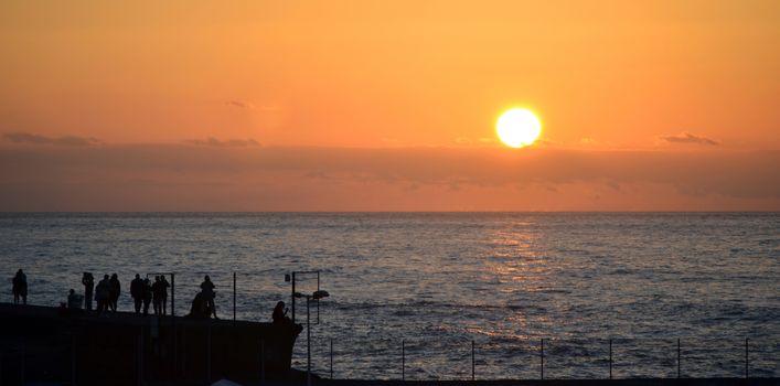 Silhouettes of people watching sunset on the Atlantic Ocean shore