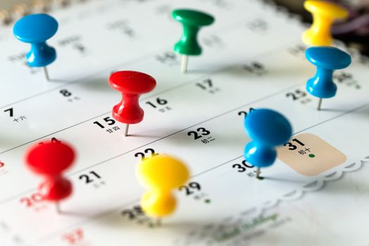 Various color thumb tack pins on calendar as reminder