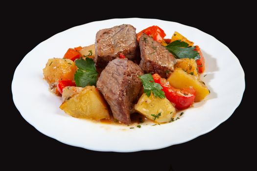 Plate with roasted meat and potatoes on a black studio background