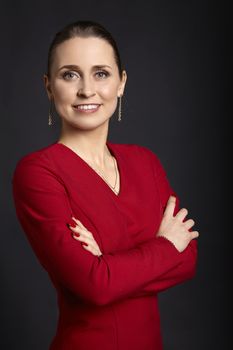 Portrait of young woman in red dress and crossed arms, looking at the camera.