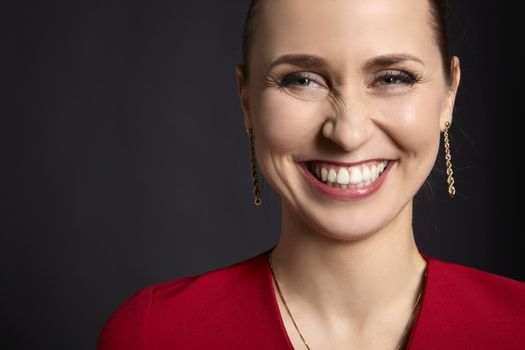 Close-up of young attractive woman with white smile on black background.