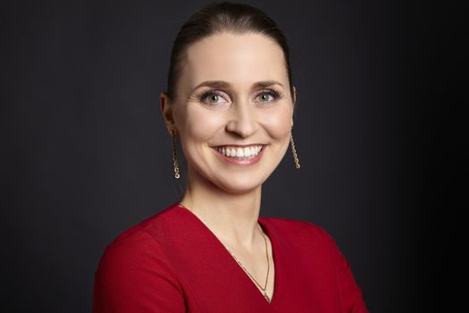 Studio shot of cheerful young woman with toothy smile on black background.