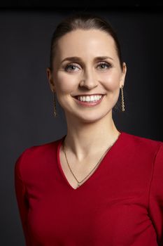 Studio shot of cheerful young woman with toothy smile on black background.