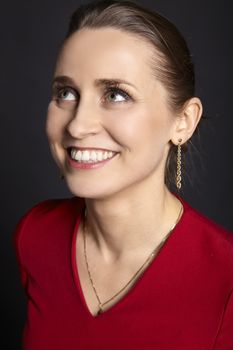 Portrait of young smiling woman with white smile and green eyes looking up. Black background.