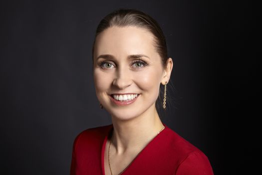 Studio shot of cheerful young woman with toothy smile on black background.