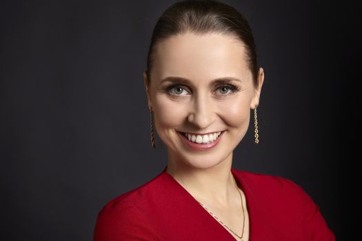 Studio portrait of young satisfied woman with white smile and green eyes on black background.