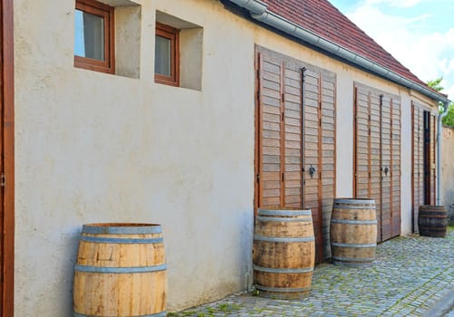 Old rustic wine barrels in front of modern wine cellar. Wine background in Europe. Czech Republic, South Moravia. 