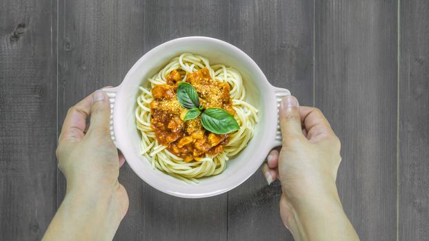 Plate of delicious spaghetti bolognese with savory minced beef and tomato sauce garnished with  basil, overhead view