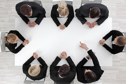 Business people sitting around empty table, business man pointing to blank copy space in the middle