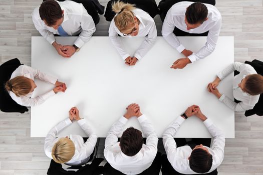 Business people sitting around empty table, business man pointing to blank copy space in the middle