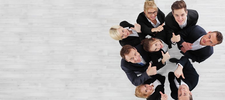 Young group of business people showing thumbs up signs in joy, top view with copy space