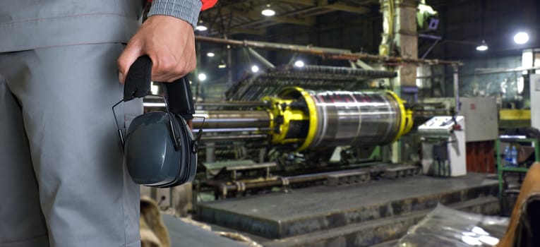 Worker with protective headphone at man hands at industrial factory