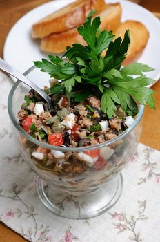 Chopped tuna with egg, cubes of tomatoes and olive slices , capers and parsley. Salad in a glass.