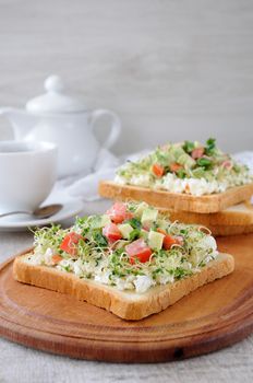 Sandwich for breakfast from tender, juicy germinated alfalfa sprouts with soft ricotta, tomato and avocado slices, with a cup of coffee or tea, which may be better for a break