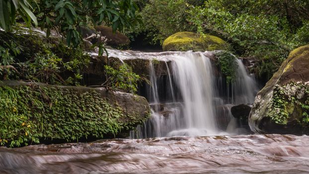 Stream in the tropical forest . Cascade falls over mossy rocks