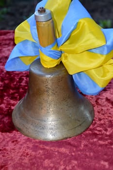 old school bronze bell with a blue and yellow bow on a velvet tablecloth