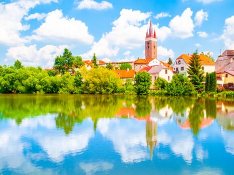 Tower of Church of the Holy Spirit in Telc on sunny summer day reflected in the water, Czech Republic. UNESCO World Heritage Site.