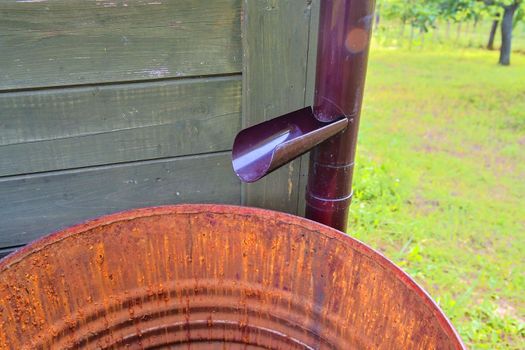 Old iron barrel and plastical gutter ready for summer rains.