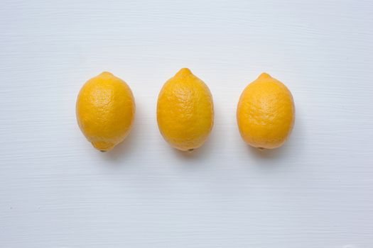 Three yellow lemons on a white background.