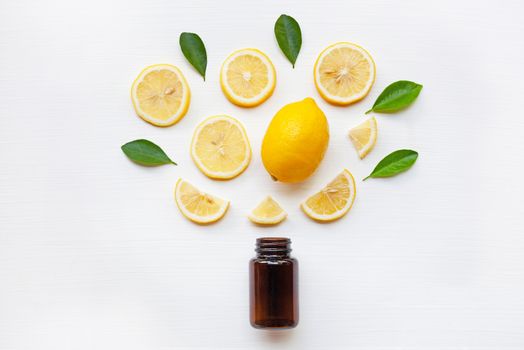 Empty medicine bottle with fresh lemon slices and leaf on white wooden background.