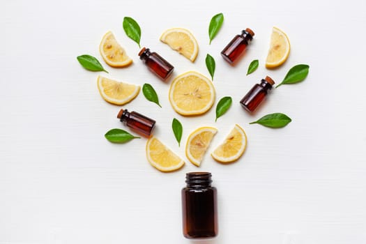 Medicine bottle with fresh lemon slices and leaf on white wooden background.