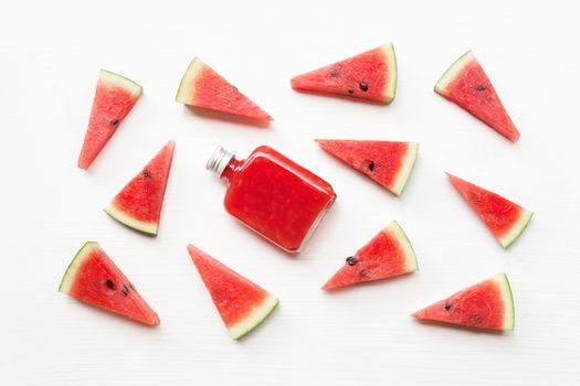 Bottle of fresh watermelon juice with  watermelon pieces  on white.