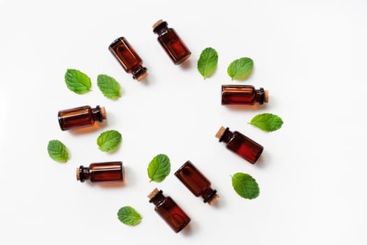 Mint Essential Oil in a Glass Bottle with leaves on white background.
