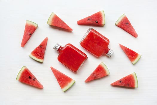 Bottle of fresh watermelon juice with  watermelon pieces  on white.