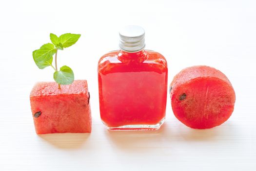 Bottle of fresh watermelon juice with  watermelon pieces  on white.