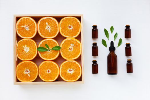 Bottle of essential oil from oranges citrus fruit with fresh orange and leaves on white background.