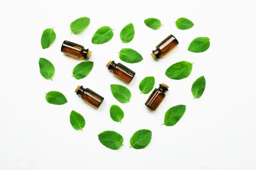 Essentail oil with fresh mint leaves on white background.