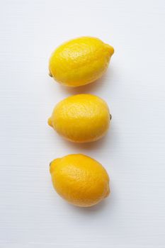 Three yellow lemons on a white background.