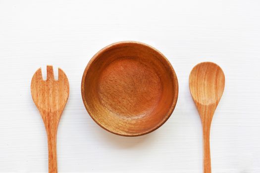 wooden dish heart shape with spoon and fork on white background.
