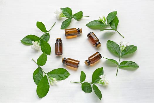 Dark brown Bottles of essential oil with jasmine flower and leaves on white background.