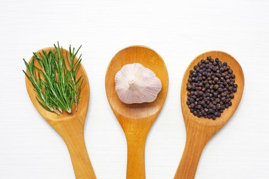Garlic with rosemary and black peppercorn isolated on white wooden background