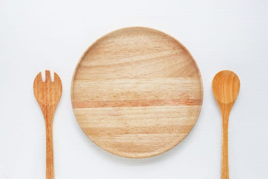Wooden plate with spoon and fork on white background.