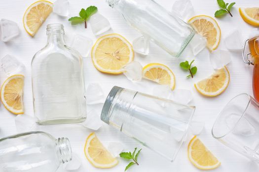 Glasses and bottle for drinks with lemon slices, mint and honey on white. Healthy vitamin drink concept.