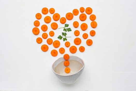 Chopped carrot slices heart shape and parsley leaves with bowl isolated on white background.