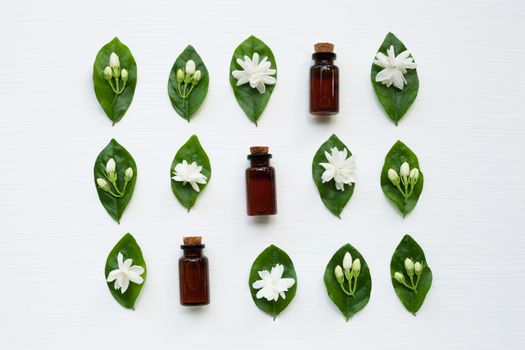 Dark brown Bottles of essential oil with jasmine flower and leaves on white background.