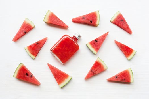 Bottle of fresh watermelon juice with  watermelon pieces  on white.