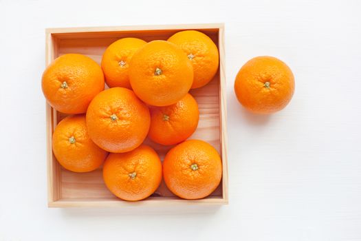 Fresh orange citrus fruit in wooden box isolated on white background.  Top view