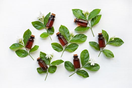 Dark brown Bottles of essential oil with jasmine flower and leaves on white background.