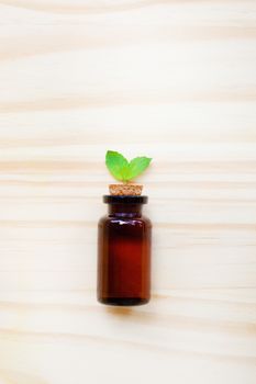 Mint Essential Oil in a Glass Bottle with leaves on white background.