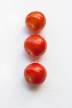 Three red  tomatoes on a white background.