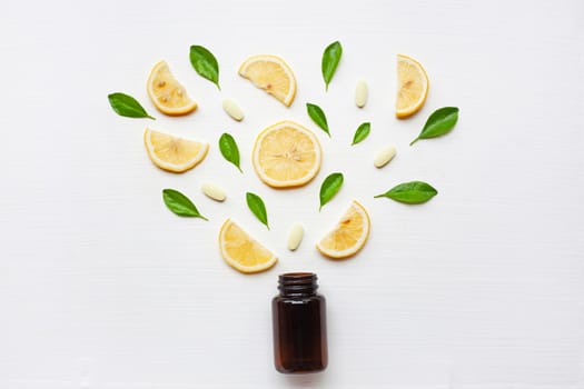Empty medicine bottle with fresh lemon, leaves and vitamin C. on white background.