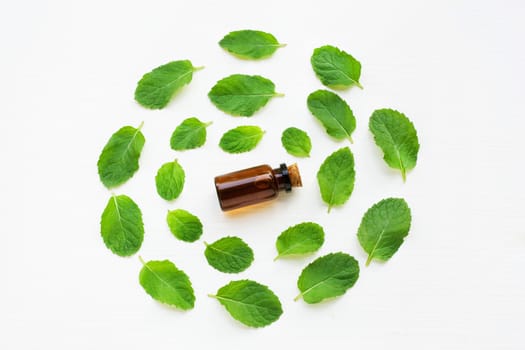 Essentail oil with fresh mint leaves on white background.
