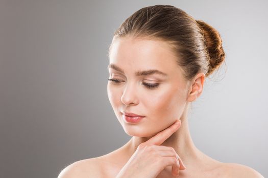 Beautiful young woman with clean fresh skin touch own face. Facial treatment. Cosmetology, beauty and spa