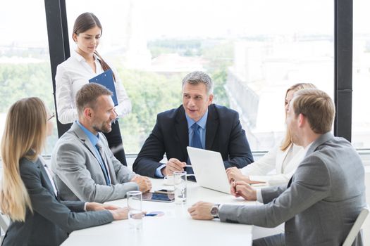 Business person group in formalwear discuss documents at meeting in modern office