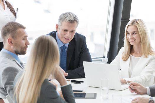 Happy business people group in formalwear discuss documents at meeting in modern office