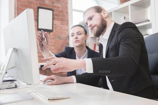 Two business people working together in the office looking at one monitor